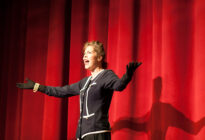 Schauspielerin auf einer Bühne vor rotem Vorhang