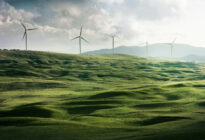 Grüne Landschaft mit Windrädern im Hintergrund.