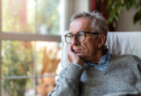 Älterer Herr sitzt auf Sessel am Fenster