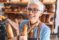 Frau beim Bäcker kauft Baguette