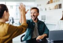 Mehrere junge Kollegen im Büro als Team freuen sich