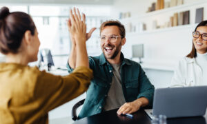 Mehrere junge Kollegen im Büro als Team freuen sich